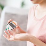 Asian woman checking blood sugar level by Digital Glucose meter,
