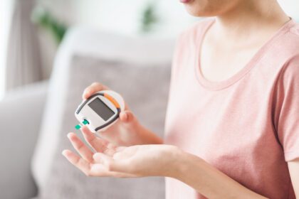 Asian woman checking blood sugar level by Digital Glucose meter,